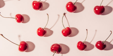 Cherries and hard shadows. Flat lay of cherries on a on a beige background.